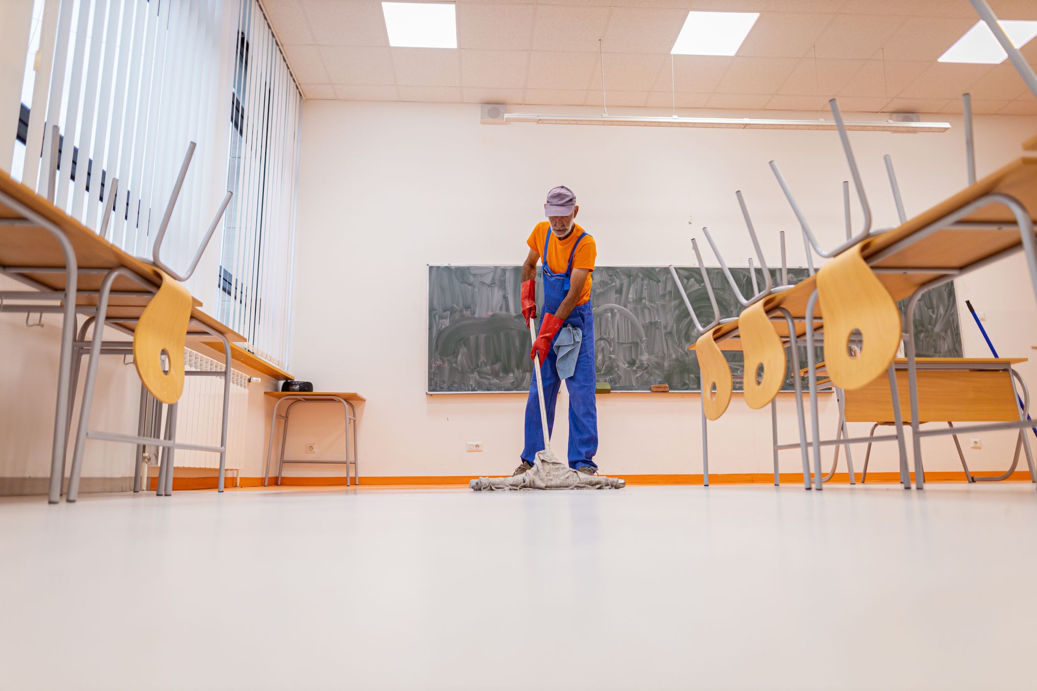 Commercial cleaner mopping the floors of a classroom setting